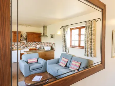a living room with two blue chairs and a mirror at Barn Owl Cottage in Little Glenham