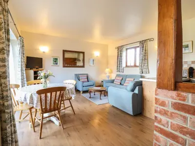 a living room with a blue couch and a table at Barn Owl Cottage in Little Glenham