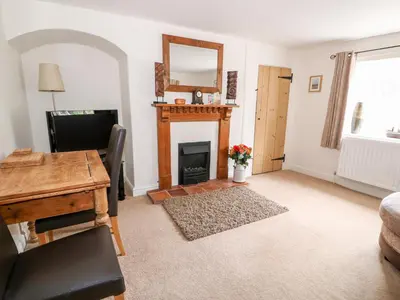 a living room with a fireplace and a desk at Flint Cottage in Swaffham