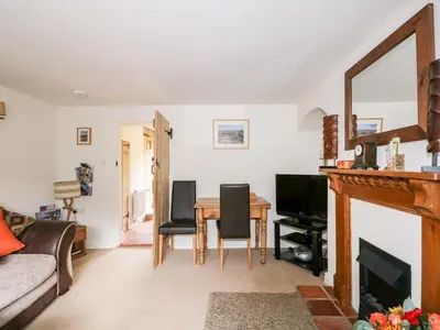a living room with a fireplace and a table at Flint Cottage in Swaffham