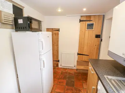 a kitchen with a white refrigerator in a room at Flint Cottage in Swaffham