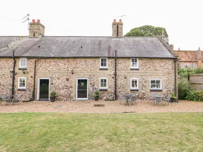 an old stone building with tables and chairs in front of it at Flint Cottage in Swaffham