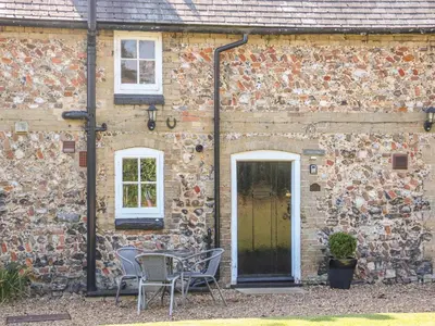 a brick building with a table and chairs in front of it at Flint Cottage in Swaffham