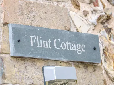 a sign on the side of a stone wall at Flint Cottage in Swaffham