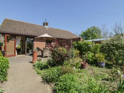 a garden with a house with an umbrella at Kingfisher in Wattisfield