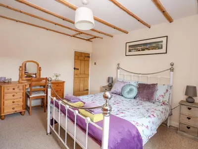 a bedroom with a bed and a desk and a chair at Holly Cottage in Swaffham