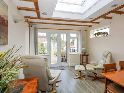 a living room with a skylight and chairs and a table at Holly Cottage in Swaffham