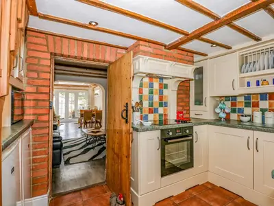 a kitchen with white cabinets and a brick wall at Holly Cottage in Swaffham