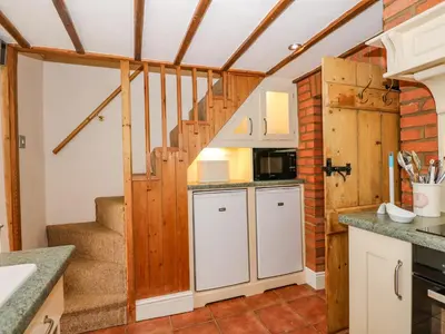 a kitchen with a staircase in a house at Holly Cottage in Swaffham