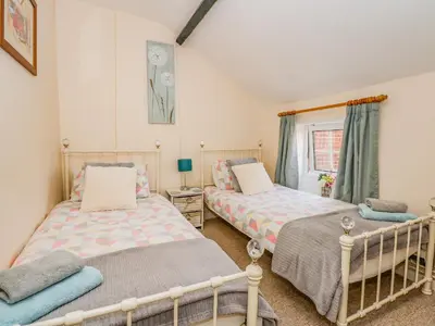 a bedroom with two beds and a window at Holly Cottage in Swaffham