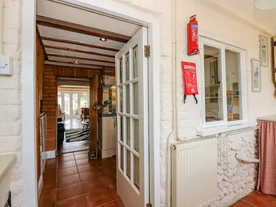 a door leading into a kitchen and a hallway at Holly Cottage in Swaffham
