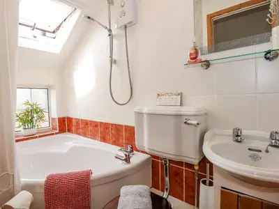 a bathroom with a tub and a sink at Holly Cottage in Swaffham