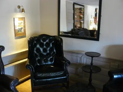a black chair and a mirror in a room at The Black Bull Inn in Balsham