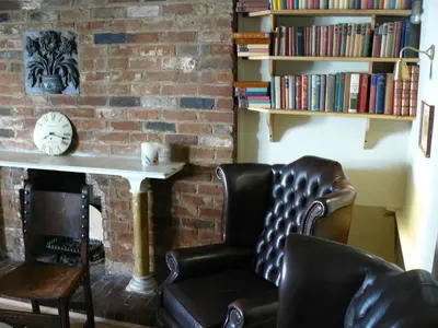 a living room with a chair and a table and a brick wall at The Black Bull Inn in Balsham