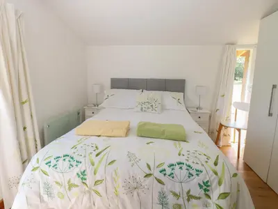 a bedroom with a white bed with a green blanket at Lakeside Lodge in East Harling