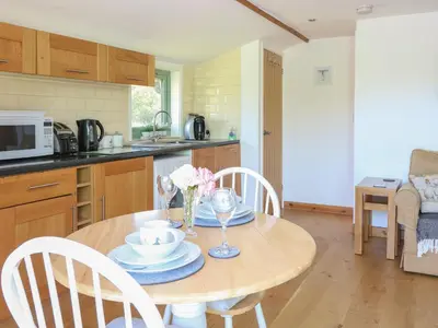 a kitchen with a wooden table with a bowl of flowers on it at Lakeside Lodge in East Harling