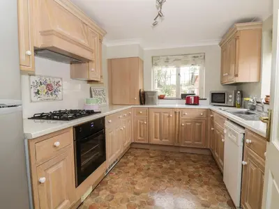 a kitchen with wooden cabinets and a stove top oven at The Lodge off High Street in Hadleigh