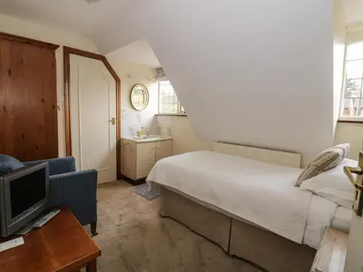 a small bedroom with a bed and a tv at The Lodge off High Street in Hadleigh