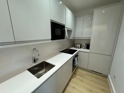 a small kitchen with white cabinets and a sink at Brentwood Hotel & Apartments in Brentwood