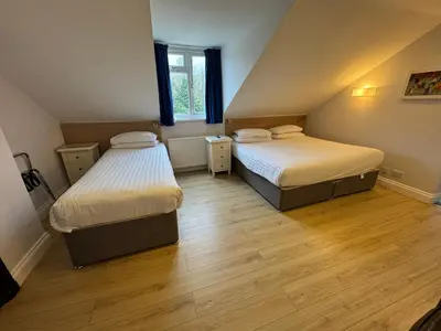 two beds in a small room with wooden floors at Brentwood Hotel & Apartments in Brentwood