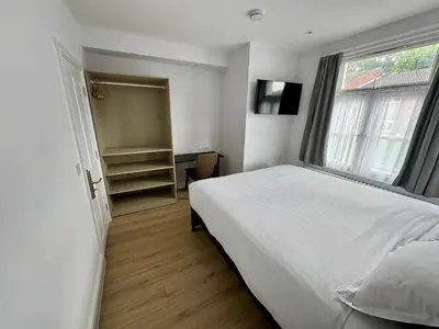 a bedroom with a white bed and a window at Brentwood Hotel & Apartments in Brentwood