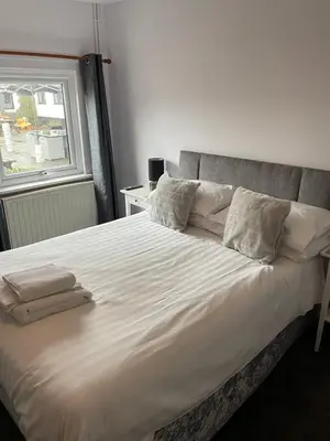 a bed with white sheets and pillows and a window at Coach house hotel in Royston