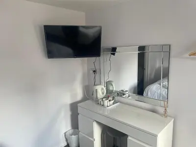 a bathroom with a sink and a tv on a wall at Coach house hotel in Royston