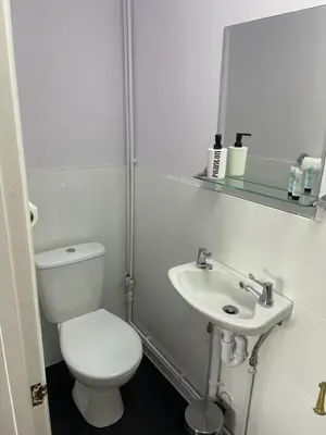a white bathroom with a toilet and a sink at Coach house hotel in Royston