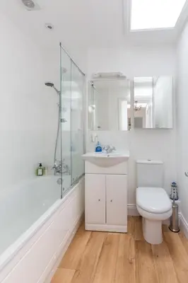 a white bathroom with a toilet and a shower at The Lobster Pot in Aldeburgh
