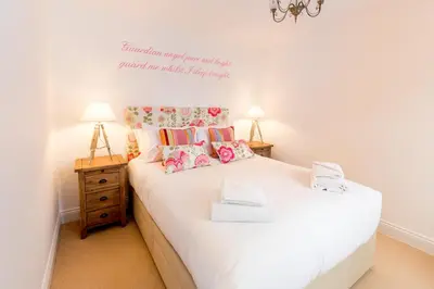 a bedroom with a white bed with flowers on the wall at The Lobster Pot in Aldeburgh