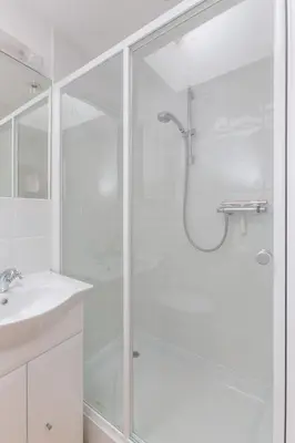 a white bathroom with a shower and a sink at The Lobster Pot in Aldeburgh
