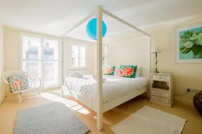 a bedroom with a white canopy bed and a chair at Shell Cottage in Aldeburgh