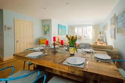 a dining room with a wooden table and blue chairs at Shell Cottage in Aldeburgh