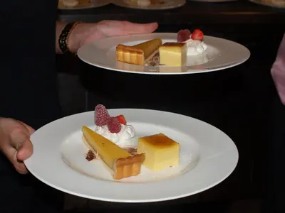 a person holding two plates of desserts on plates at The Bull at Great Totham Limited in Great Totham