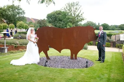 a bride and groom standing next to a statue of a bull at The Bull at Great Totham Limited in Great Totham