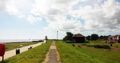 a dirt road next to a beach with a building at On the Quay in Harwich