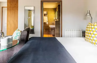 a bedroom with a bed and a table and a bathroom at Crown and Castle in Orford