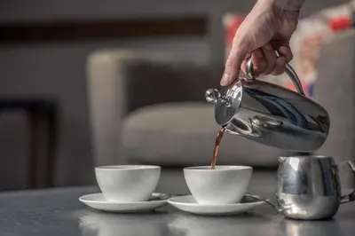 a person pouring coffee into two cups on a table at Crown and Castle in Orford
