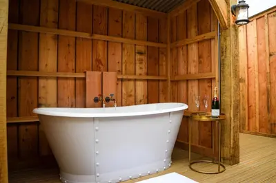 a bath tub in a room with wooden walls at Retreat East in Ipswich