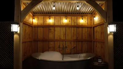 a bath tub in a wooden bathroom with lights at Retreat East in Ipswich