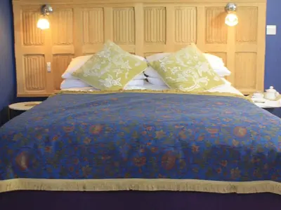a bed with a blue blanket and pillows on it at The Lodge at Hemingford Grey House in Hemingford Grey