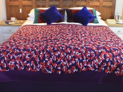 a bed with a blue and red blanket with blue pillows at The Lodge at Hemingford Grey House in Hemingford Grey