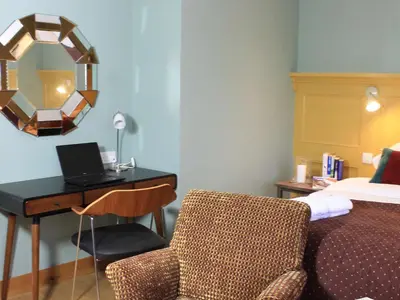 a hotel room with a desk with a laptop and a bed at The Lodge at Hemingford Grey House in Hemingford Grey