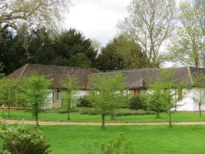a house with trees in front of it at The Lodge at Hemingford Grey House in Hemingford Grey