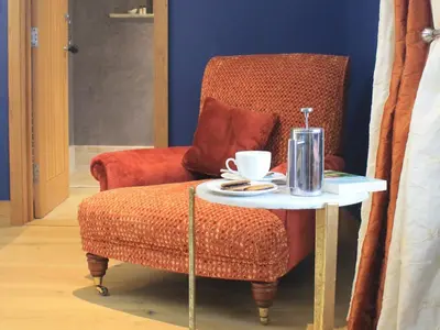 a table and a chair with a coffee cup on it at The Lodge at Hemingford Grey House in Hemingford Grey