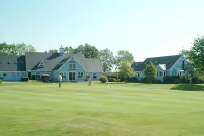 two people playing golf on a green in front of a house at Richmond Park Golf Club in Watton