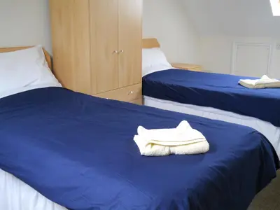 a bedroom with two beds with blue sheets and white towels at Richmond Park Golf Club in Watton