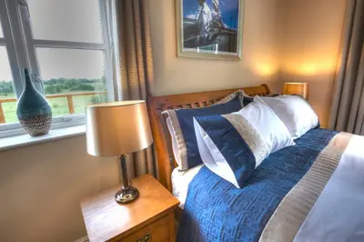 a bedroom with a bed with a lamp and a window at Sunset House Bed and Breakfast in East Harling