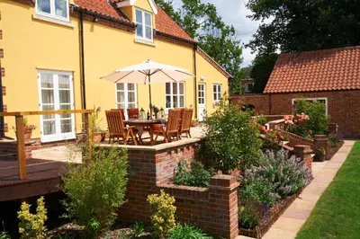 a patio with a table and an umbrella in a yard at Sunset House Bed and Breakfast in East Harling