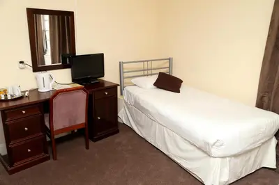 a bedroom with a bed and a desk with a television at Rose and Crown Hotel in Haverhill